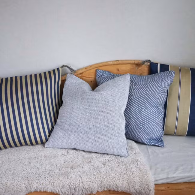 Leinenkissen von Klässbols Linneväveri in Blautönen auf einem Küchensofa.