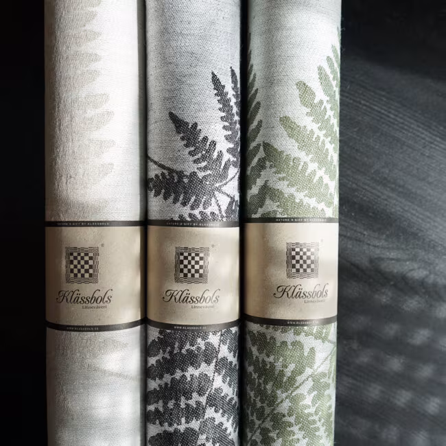 Ormbunke table runners rolled up, in the colors black, black, moss green, by Klassbols Linnevaveri