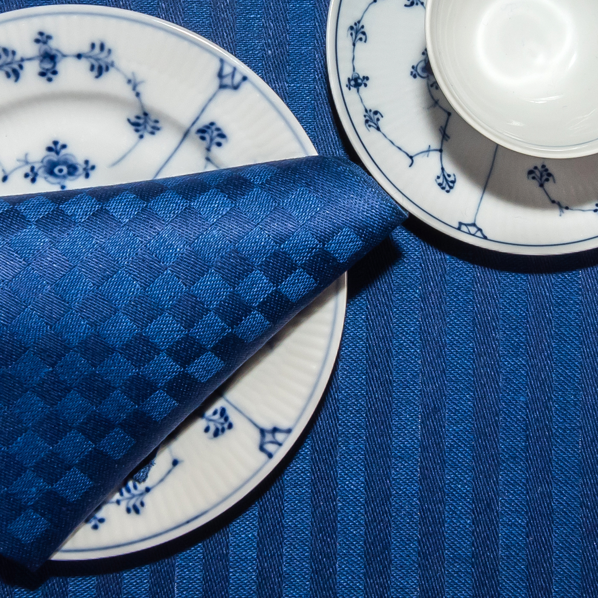 Blå ordern linne servetter tabletter på tallrik med bestick Klässbols Linneväveri Hanne Vedel bordsdukning tillsammans med kaffe och vitt och blått porslin