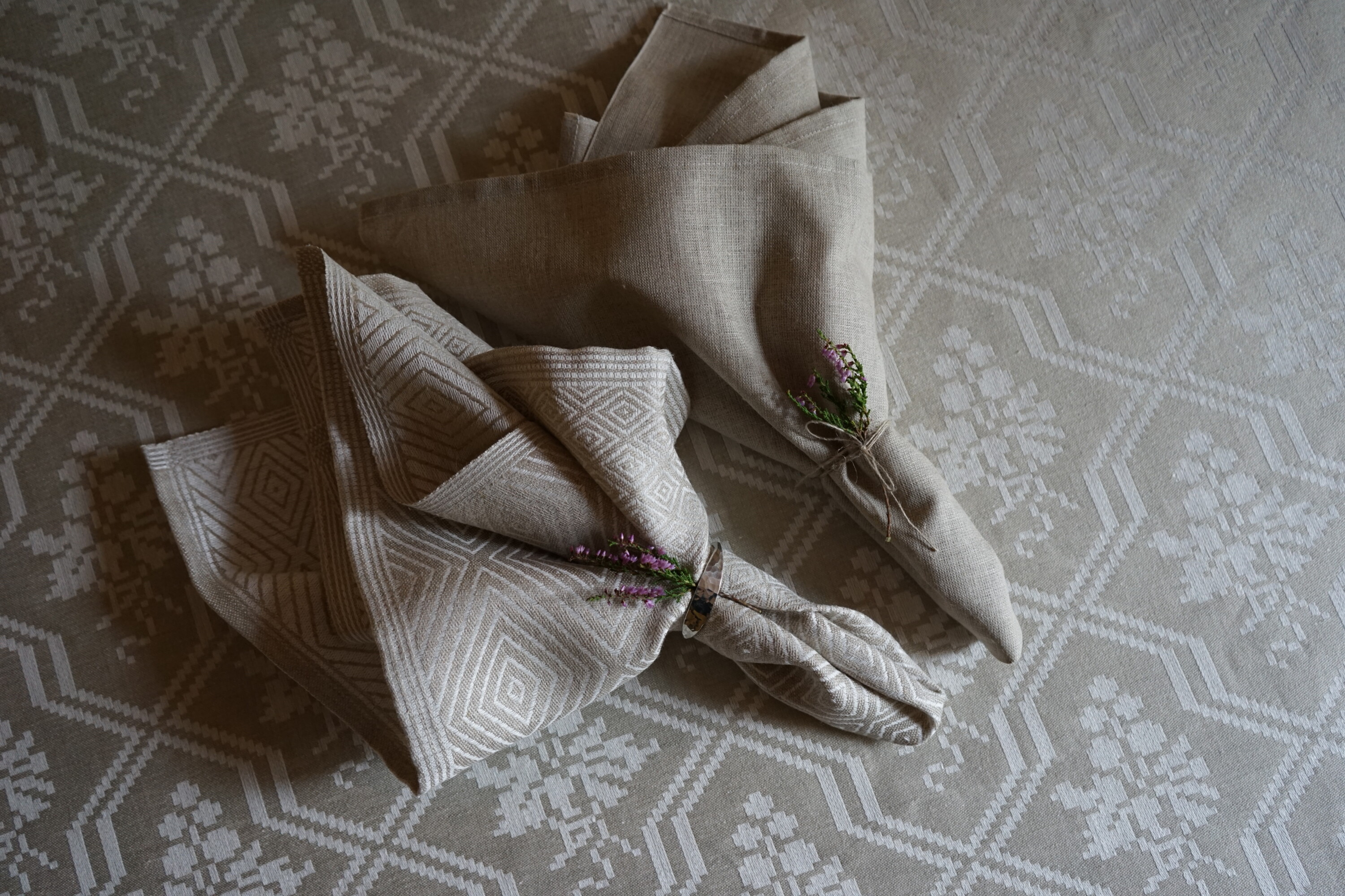 En Gåsöga och en Rustik servett i en enkel servettvikning, en lilja pryder som detalj - klässbols linneväveri